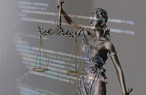 Layered image of a Lady Justice statue overlaid with computer code.