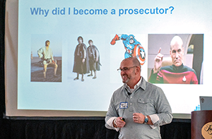 Dan Davis of Justice Innovation Lab speaking in front of a slide titled, "Why did I become a prosecutor"